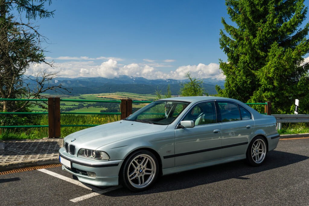 idabrinis BMW 5 serijos (E39) sedanas su M-stiliaus ratlankiais vaizdingame fone – profesionalus BMW automobilių supirkimas Lietuvoje.