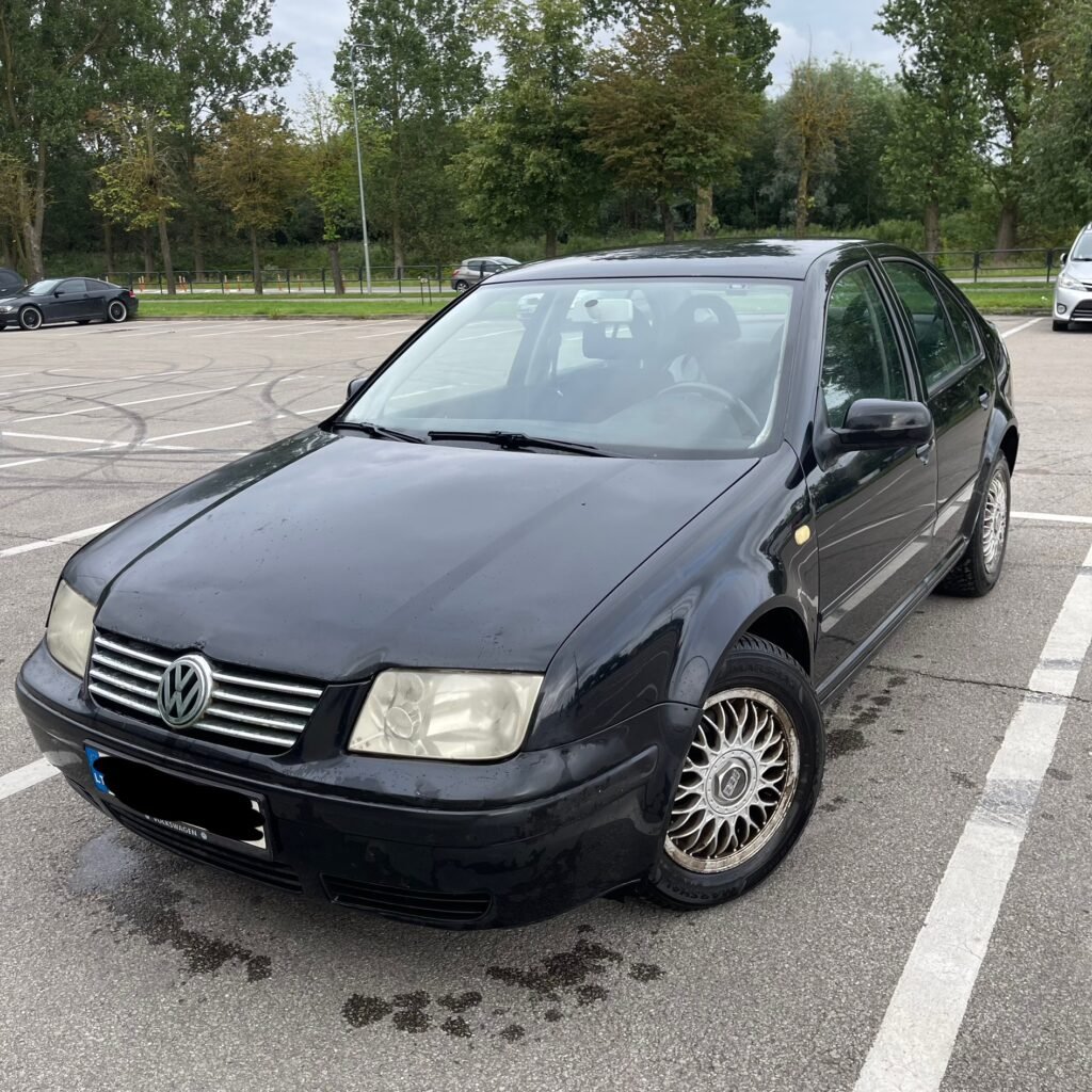 Juodas Volkswagen automobilis stovėjimo aikštelėje, paruoštas automobilių supirkimui ir utilizacijai per AutoDylas.